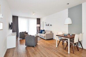 Ett modernt vardagsrum med en soffa, ett litet bord och en matplats med stolar.