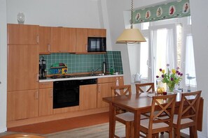 A kitchen with wooden cabinets, a microwave, a sink, and a dining table with chairs.
