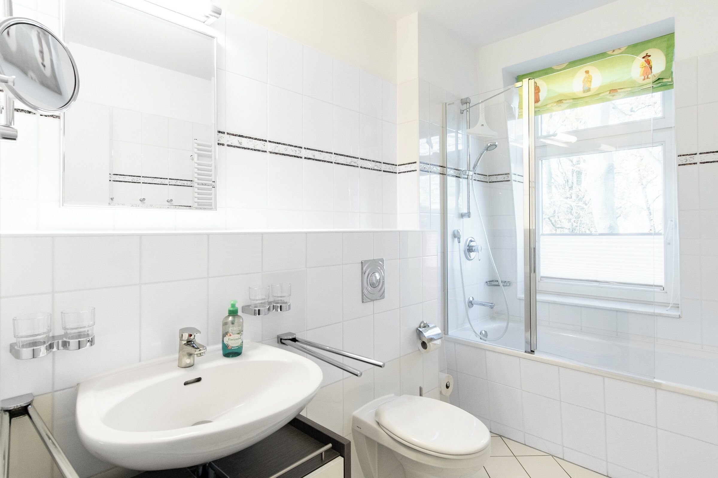 Un baño moderno con lavamanos, inodoro y cabina de ducha de vidrio.