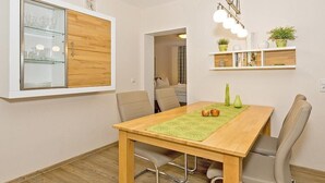 Un coin repas comprenant une table en bois, des chaises et un meuble vitré avec des étagères.