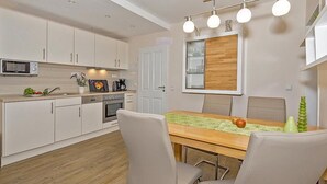 Une cuisine moderne avec des meubles blancs, un four à micro-ondes, une cuisinière et un coin repas comprenant une table et des chaises en bois.