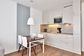 Una cocina moderna con armarios blancos, una mesa de comedor de madera y una lámpara colgante.