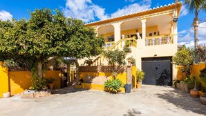 A two-story building with a yellow facade, a gated entrance, and a covered balcony. - Villa Las Palomas - Three Bedroom Villa, Sleeps 6 (Frigiliana)