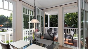 Ein sonnendurchflutetes Zimmer mit Glastisch, Stühlen und einer Pendelleuchte.