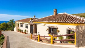 A two-story building with a tiled roof, a balcony with a railing, and a paved driveway. - Villa Las Palomas 2 - Three Bedroom Villa, Sleeps 5 (Frigiliana)