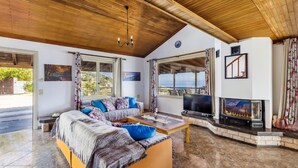 Ein gemütliches Wohnzimmer mit Holzboden, einer blauen Kissensofa, einem Kamin und einem Fernseher.