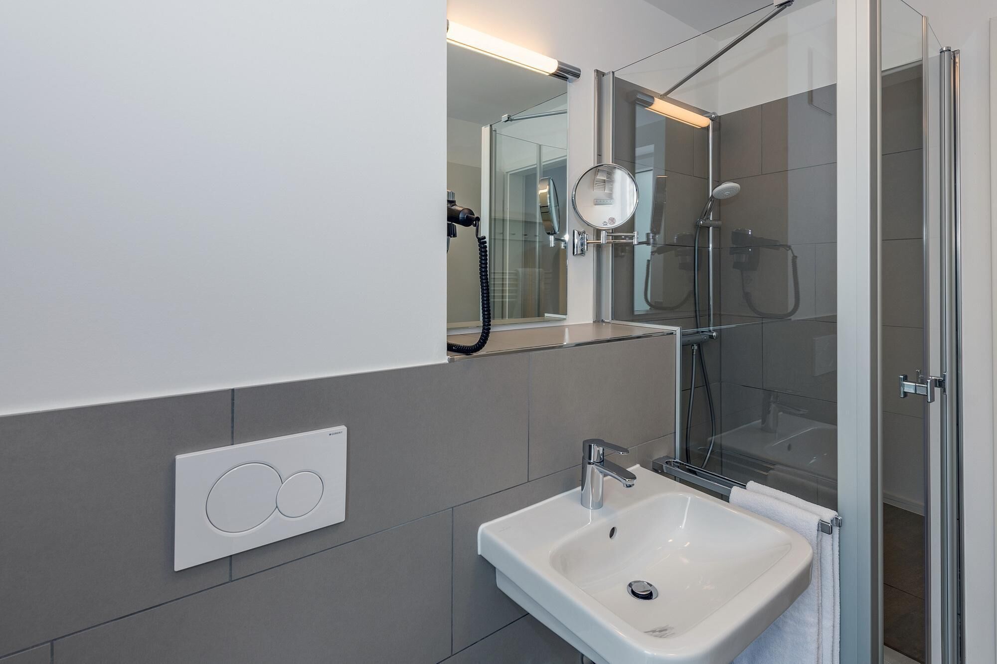 A modern bathroom with a glass-enclosed shower, a white sink, and a mirror above the sink.