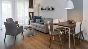 Un salon moderne comprenant un canapé, des fauteuils, une table à manger et un luminaire suspendu.