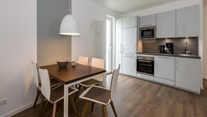 Une cuisine moderne avec des meubles blancs, un four encastré et un four à micro-ondes.