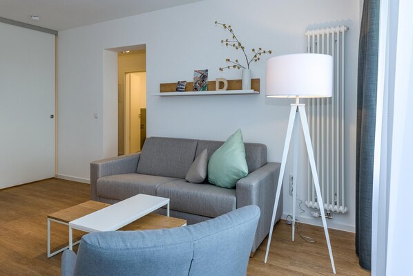 Un salon moderne avec un canapé gris, une petite table et un lampadaire.