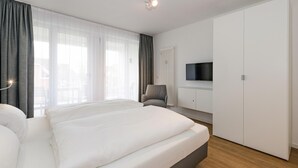 Une chambre d’hôtel moderne dotée d’un grand lit, d’un téléviseur à écran plat fixé au mur et d’une armoire.