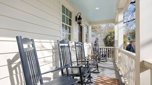 A covered porch with wooden benches and a white railing. - Historic Charleston Single w/ Private Outdoor Space (Charleston)