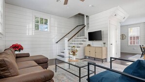 A modern living room with a brown leather sofa, a blue armchair, a glass coffee table, and a wooden cabinet. - Historic Charleston Single w/ Private Outdoor Space (Charleston)