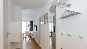 Un couloir moderne avec un plancher en bois, des murs blancs et un coin repas comprenant une table et des chaises.