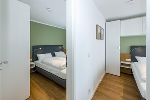 Een moderne hotelkamer met een bed, nachtkastjes, een kledingkast en een plafondlamp.