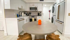 A modern kitchen with white cabinetry, a central island with a round table, and built-in appliances.