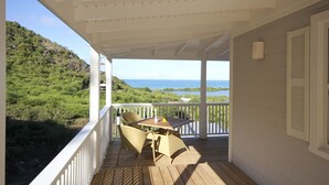 A covered porch with a table and chairs, overlooking a lush landscape and the sea. - Calabash 4 Bedroom Villa - Stunning Sea Views, Private Pool, Delightful Location (Darkwood Valley)