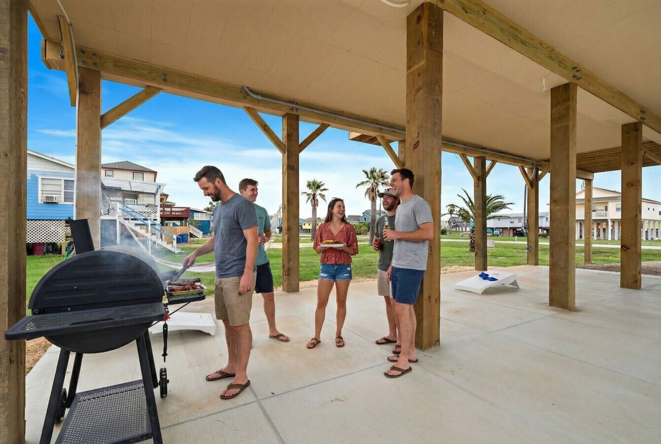 Un espacio al aire libre techado con una parrilla y gente reunida alrededor.