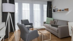 A modern living room with a grey sofa, two armchairs, a white coffee table, and a floor lamp.