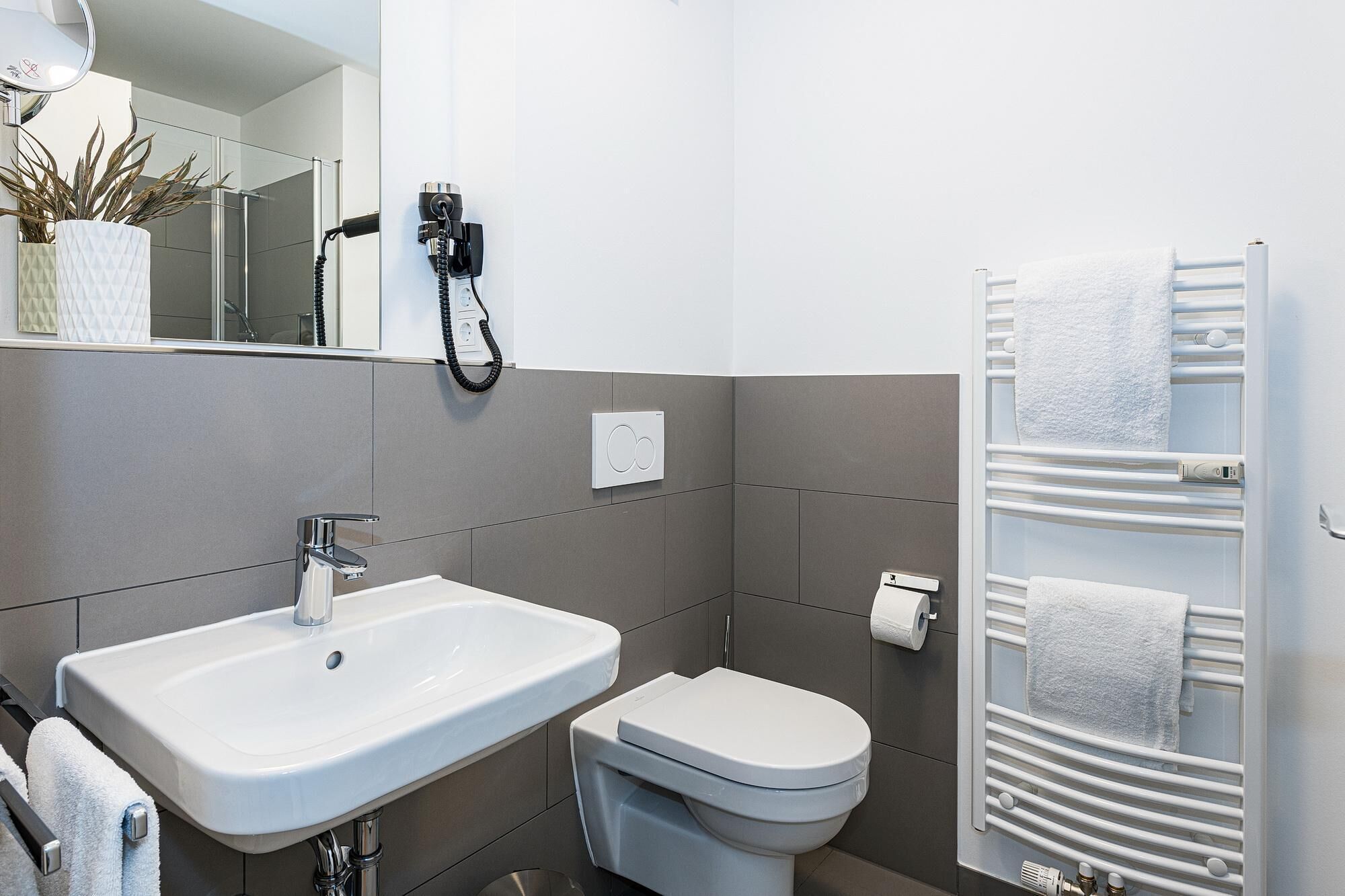 A modern bathroom with a white sink, a toilet, and a towel rack.
