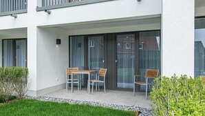 Een modern gebouw met balkon, een tafel en twee stoelen.