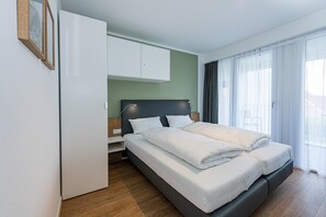 Una habitación de hotel moderna con una cama, un armario y una ventana con cortinas.