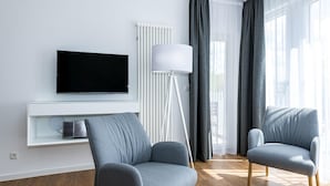 Una sala de estar moderna con un televisor de pantalla plana, una lámpara de pie y dos sillones grises.