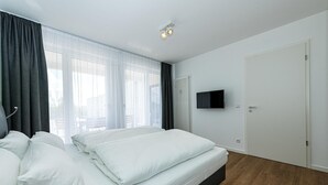 Habitación de hotel moderna con una cama grande, un televisor de pantalla plana y vistas al exterior a través de amplias ventanas.