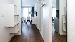 Un couloir moderne avec des murs blancs, un plancher en bois et des étagères intégrées.