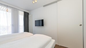 Une chambre d’hôtel avec un lit, un téléviseur fixé au mur et une porte coulissante.
