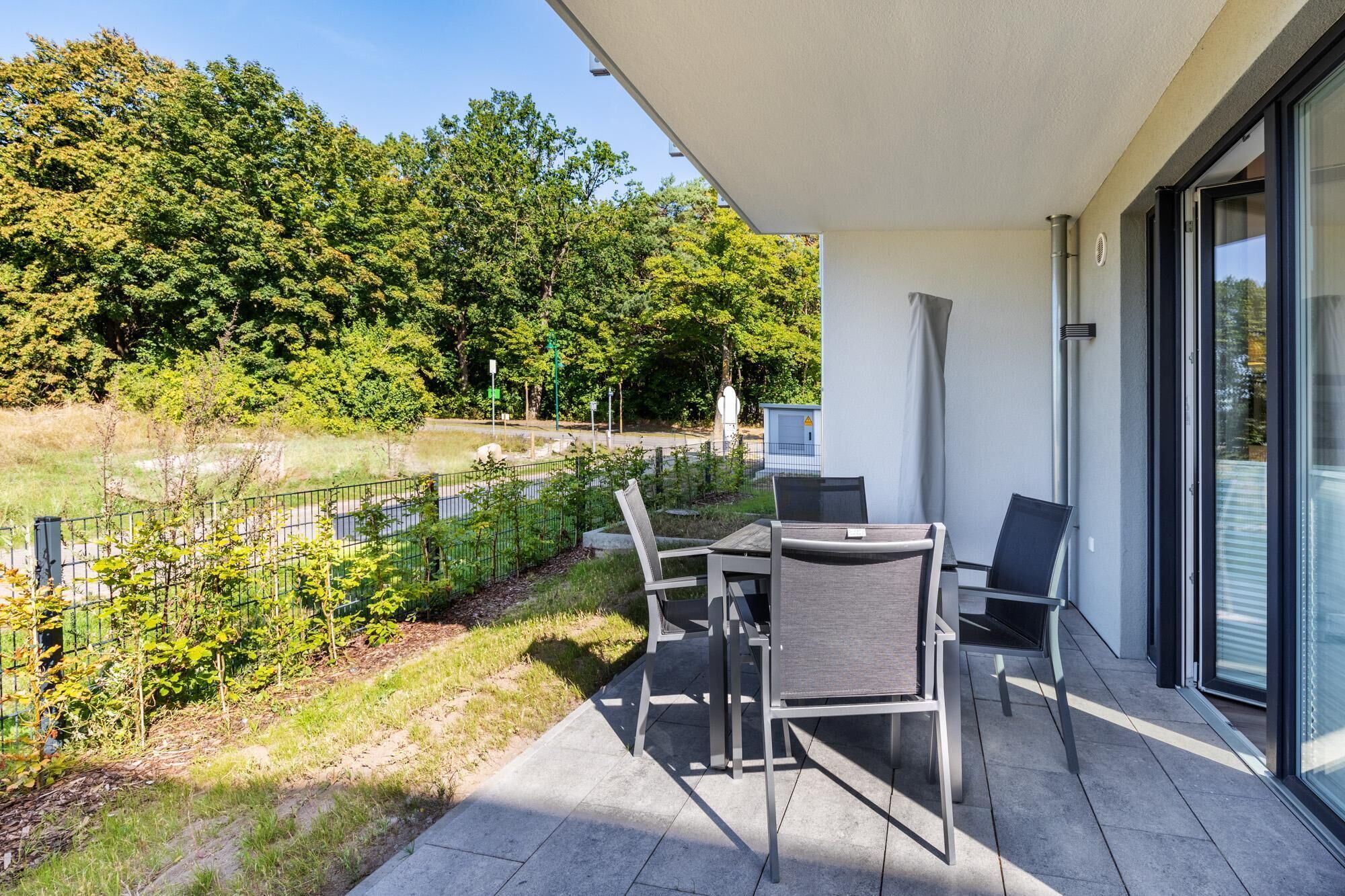 A balcony with a table and chairs, overlooking a river and trees.