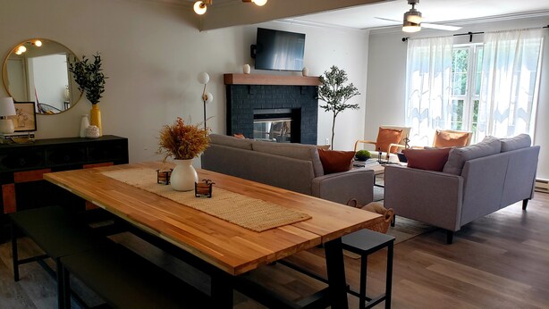 Una sala de estar moderna con una mesa de comedor de madera, sofás y una chimenea.