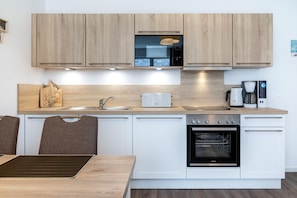 Una cocina moderna con armarios de madera, horno empotrado, cafetera y tostadora.