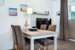 Un espace repas comprenant une table, des chaises, un bol, une lampe suspendue et des œuvres d’art accrochées au mur.