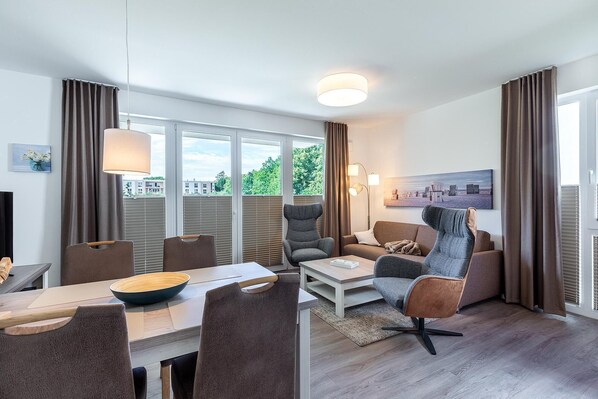 Un salon moderne avec un coin repas, de grandes fenêtres et une vue sur la verdure.