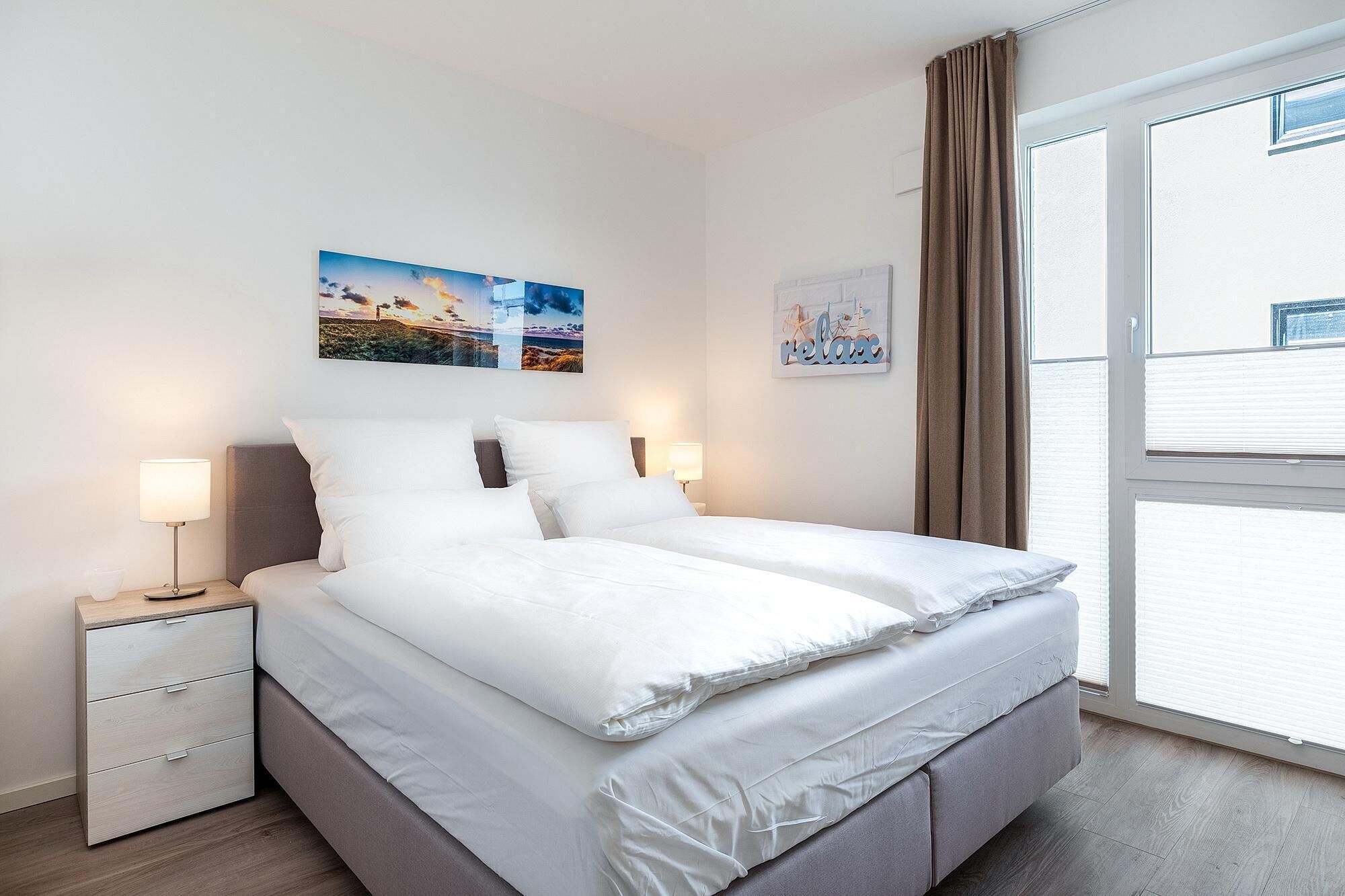 Un dormitorio moderno con una cama grande, mesitas de noche y obras de arte en las paredes.