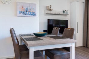 Un comedor con una mesa de madera, dos sillas, un tazón y un televisor al fondo.