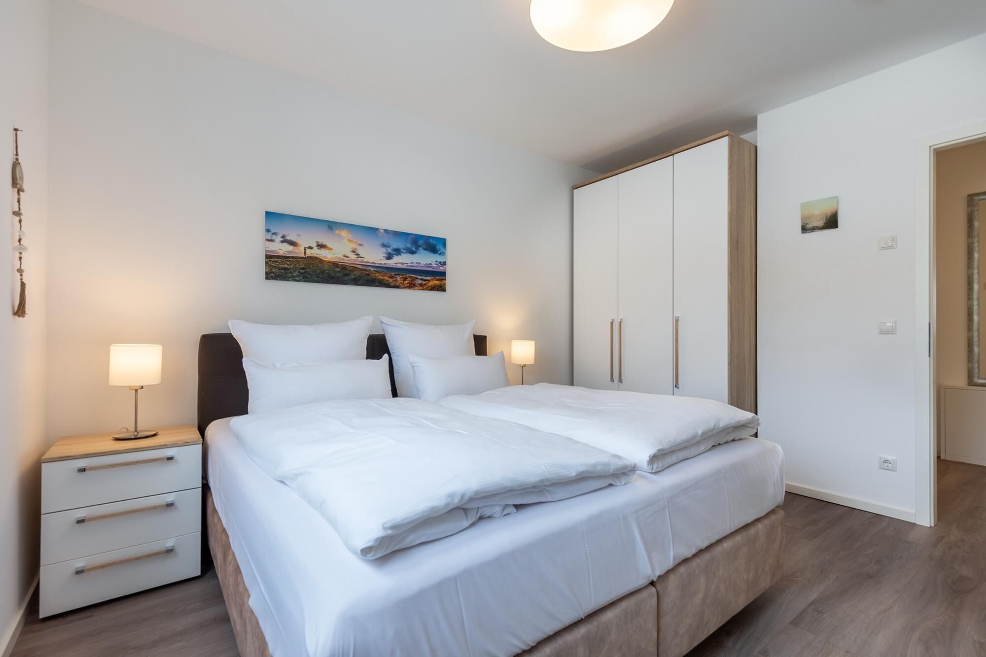 Ein Schlafzimmer mit einem Bett, Nachttischen, einem Kleiderschrank und einem Bild an der Wand.