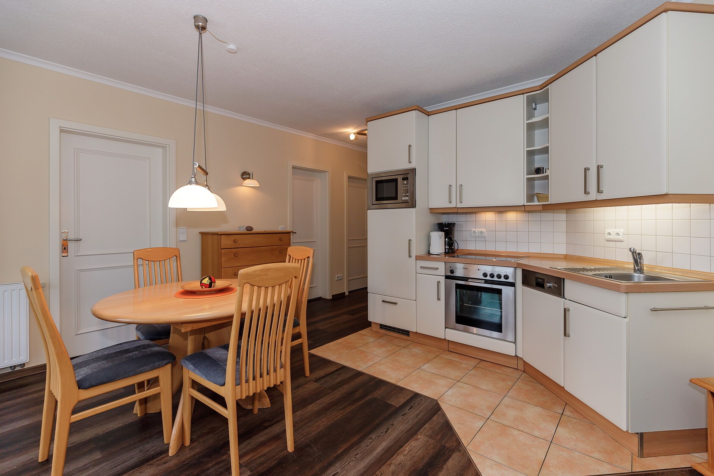 A compact kitchen with white cabinets, a microwave, an oven, and a sink.