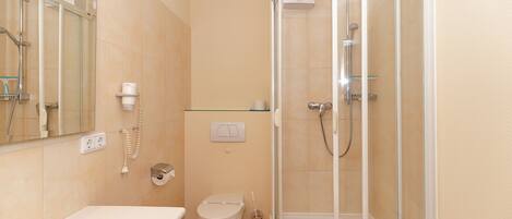 A bathroom with a bathtub, toilet, and a glass-enclosed shower stall.