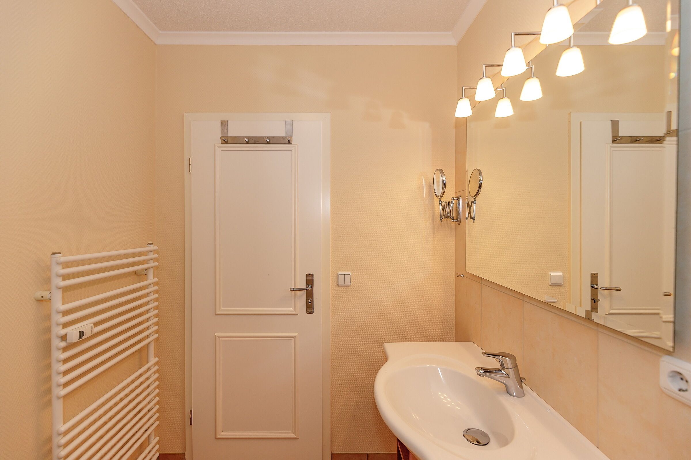 A bathroom with a white sink, a mirror, and a towel rack.