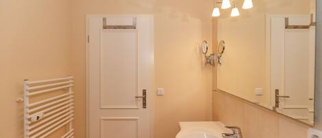A bathroom with a white sink, a mirror, and a towel rack.