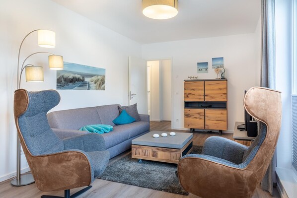 A modern living room with a grey sofa, two brown armchairs, a coffee table, and a wooden cabinet.
