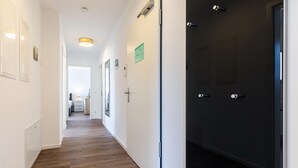 A hotel hallway with wooden flooring, white walls, and a dark door on the right. - Strandnahes Familienapartment mit Toller, Sonniger Dachterrasse und Zwei Bädern (Ostseebad Boltenhagen)