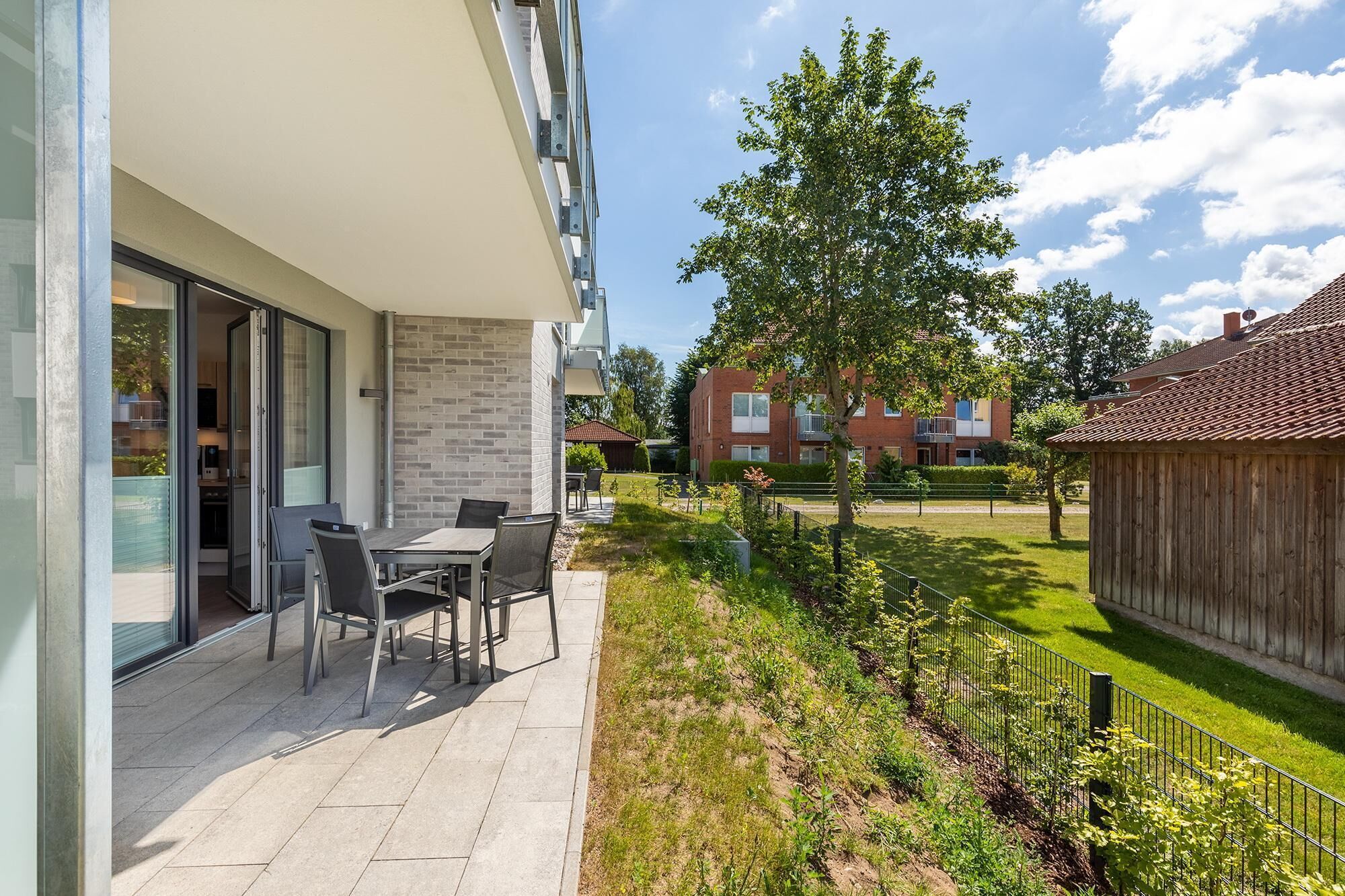 A modern apartment with a patio, outdoor furniture, and a view of neighboring buildings.