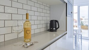Eine Küche mit weiß gefliestem Spritzschutz, einer Weinflasche, einem Weinglas und einer Kaffeemaschine auf der Arbeitsfläche.