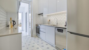 Eine moderne Küche mit weißen Schränken, einem Edelstahlkühlschrank, einer Spülmaschine und einer gefliesten Spritzschutzwand.