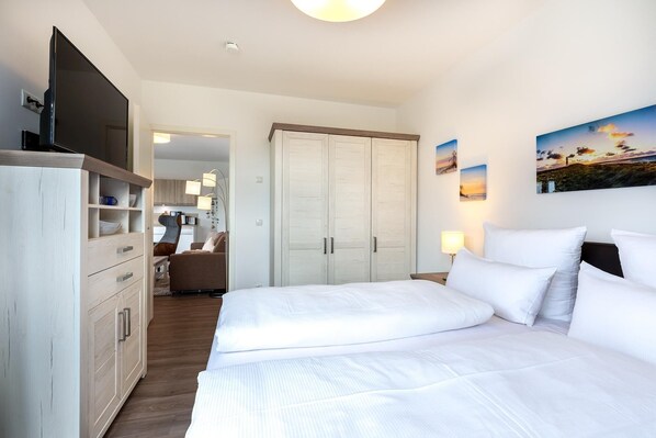 Habitación de hotel con cama, armario, escritorio con silla, kitchenette pequeña y vista al mar.