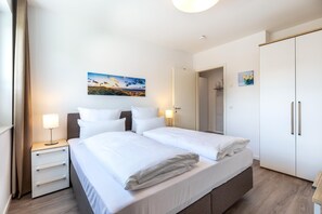 Habitación de hotel con una cama grande, una mesita de noche, un armario y un cuadro en la pared.