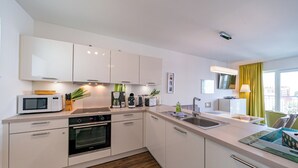 A modern kitchen with white cabinets, a microwave, a coffee maker, and a sink. - Great apartment with infrared sauna and balcony with a wonderful panoramic view! (Nordseeheilbad Schillig)